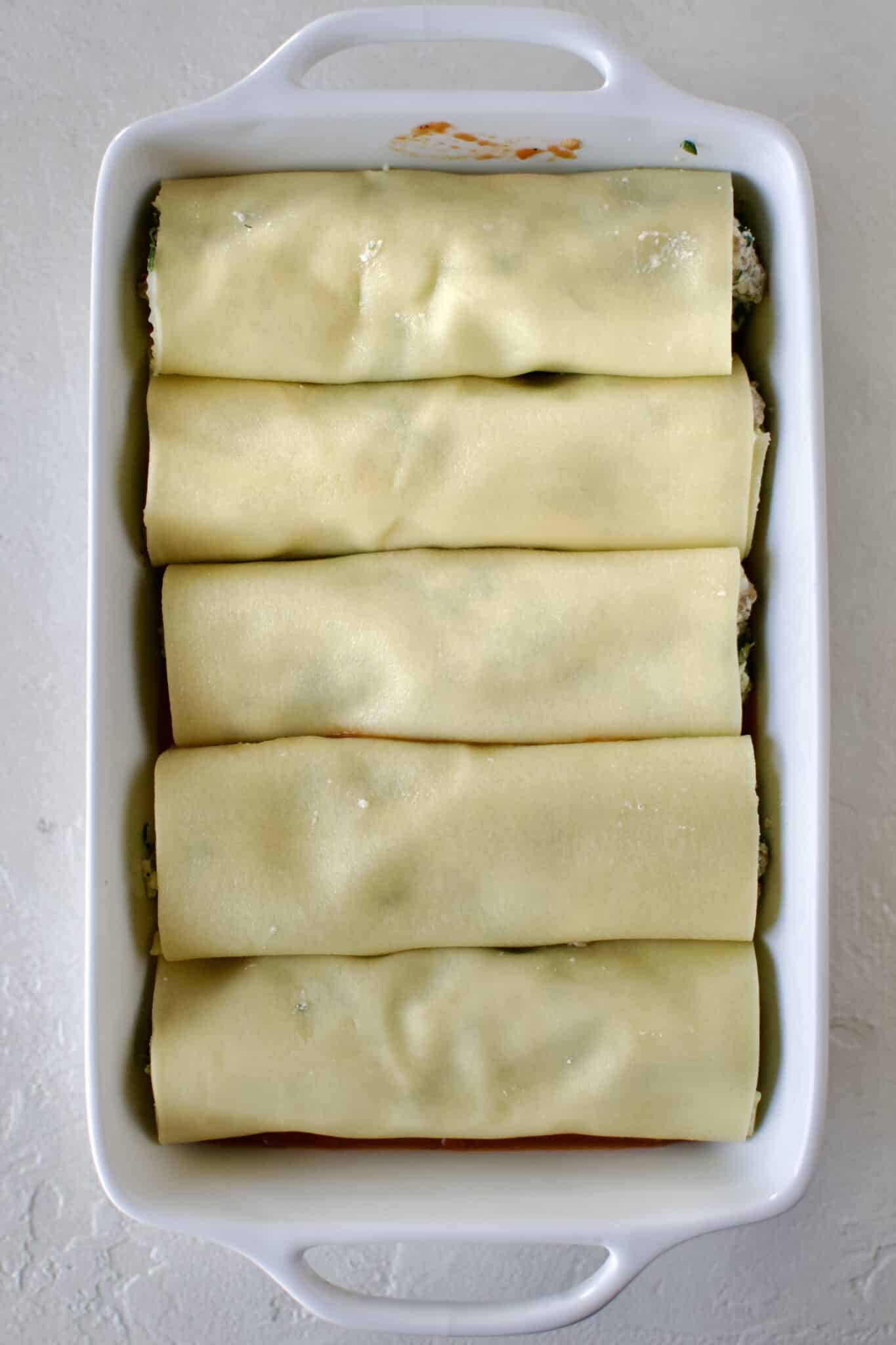 Full dish of manicotti ready to be topped with red sauce and cheese.