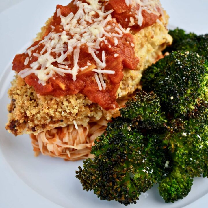 Chicken Parmesan, front view with a side of broccoli and pasta with sauce.