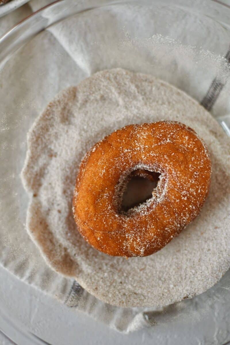 Dusting the donuts with the pumpkin spice sugar.