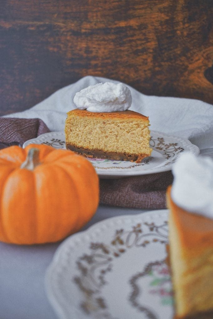 Perfect Pumpkin Cheesecake, a single slice behind a pumpkin on grandmas china