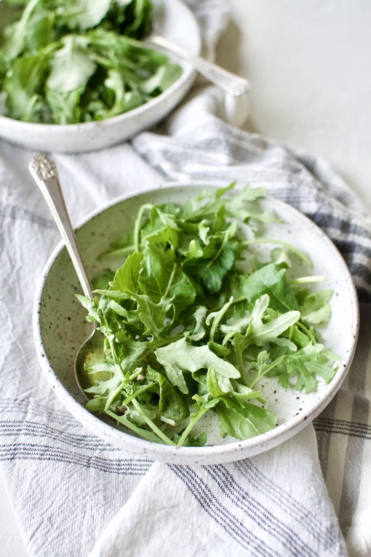 Baby Kale in a bowl waiting to be topped with Zuppa Toscana Soup.