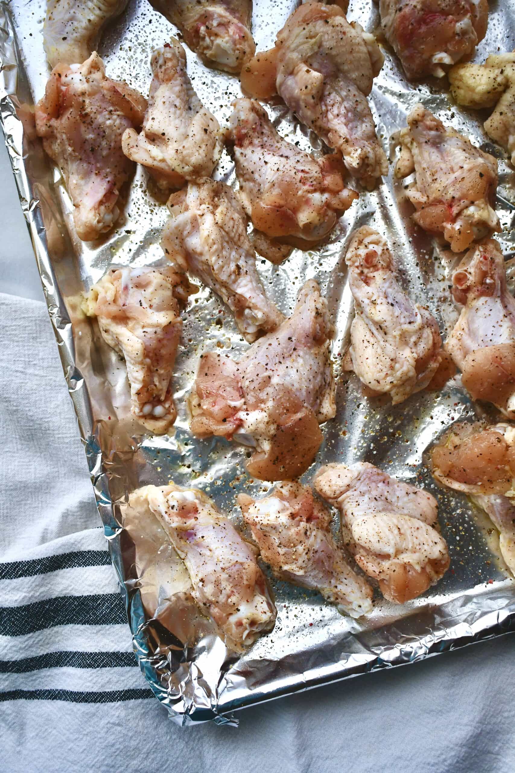 Dried and Seasoned chicken wings on a foil lined baking tray.