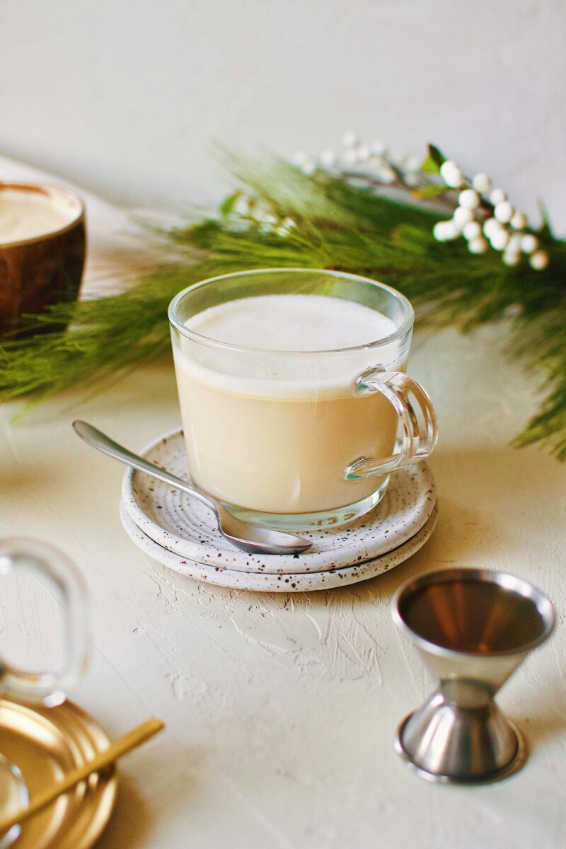 Hot buttered rum on a plate with a spoon. With a shot of rum on the side.