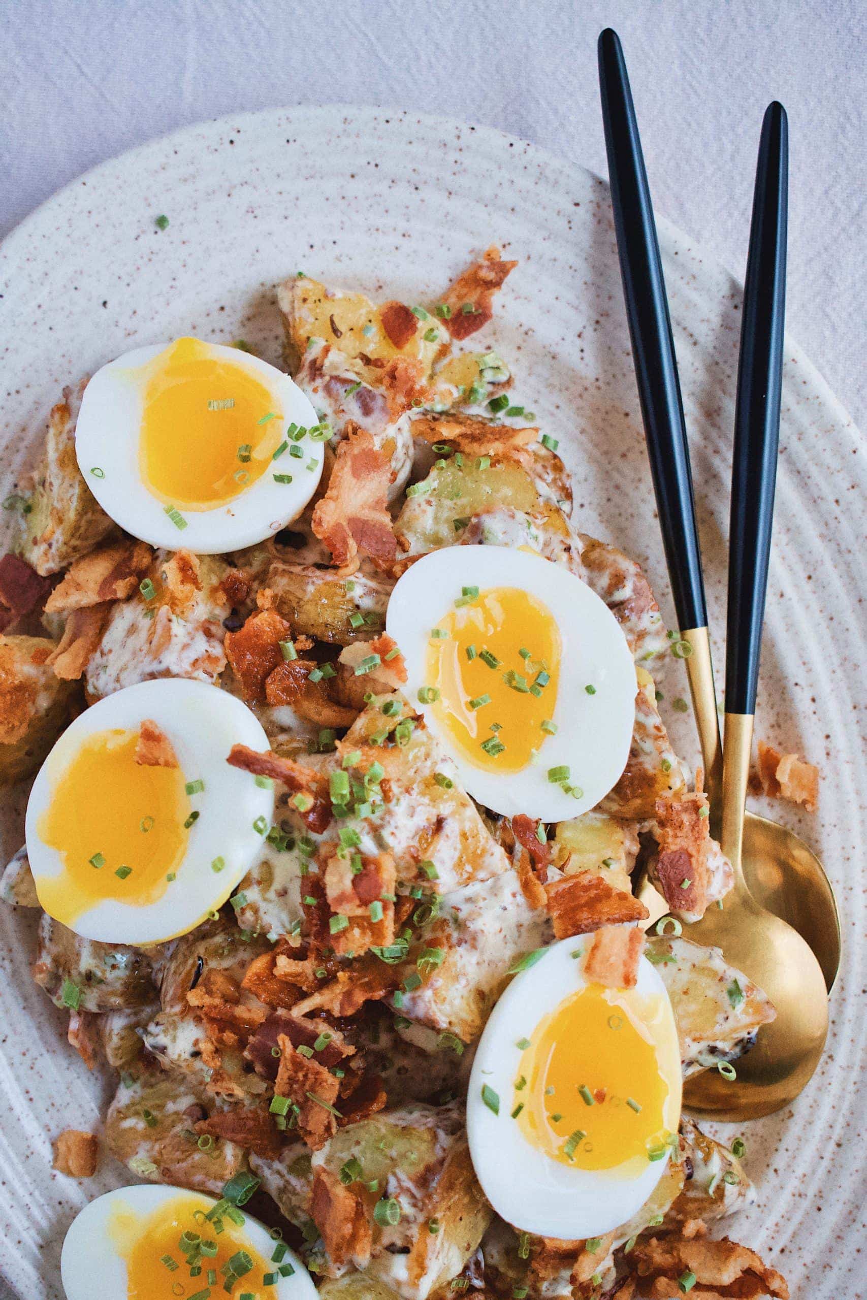 Roasted Potato Salad on platter topped with runny boiled eggs.