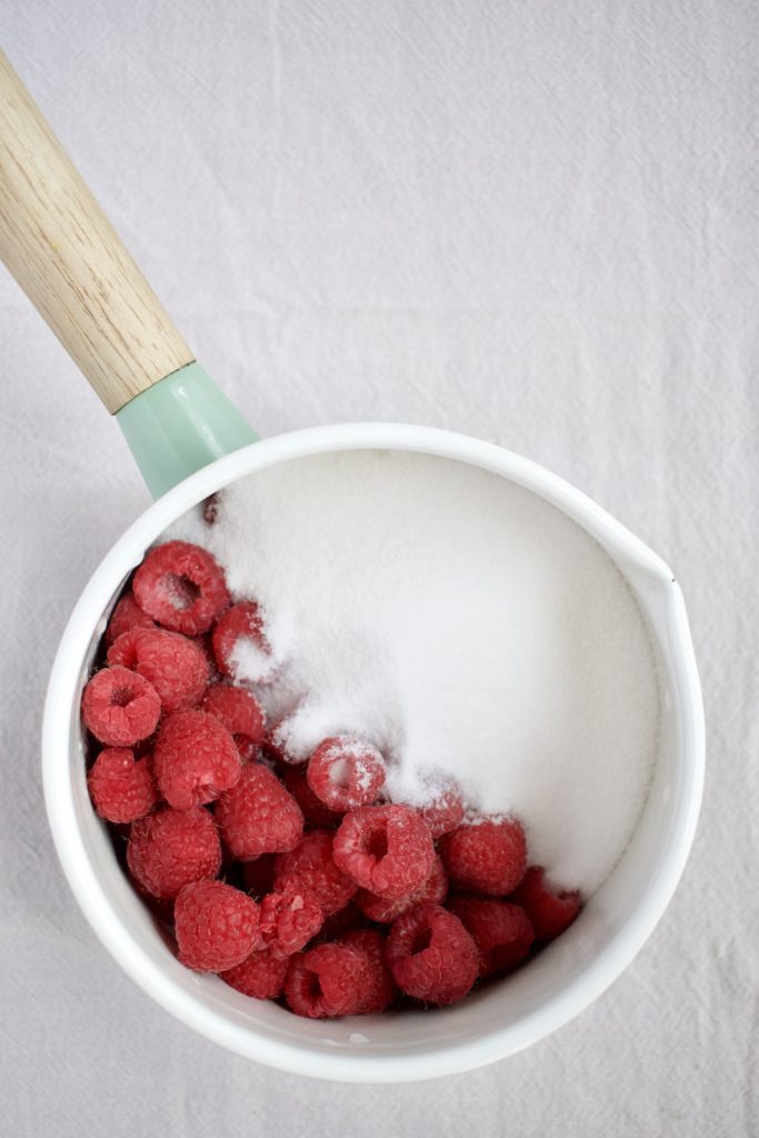 the beginning of raspberry jam, raspberries and sugar in the bottom of a pot