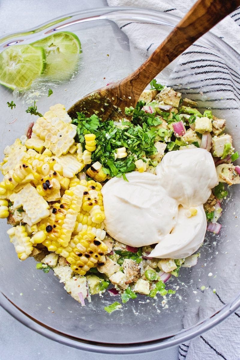 street corn being added to the chicken salad mixture