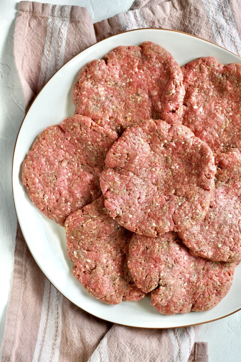 Pattied out burgers on a large platter.