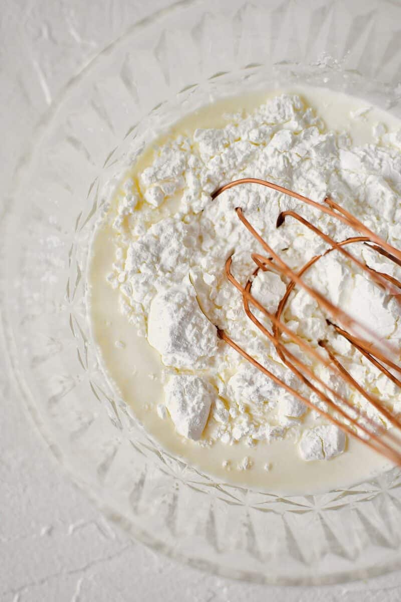 Whisking together some heavy cream and cornstarch to make a slurry.