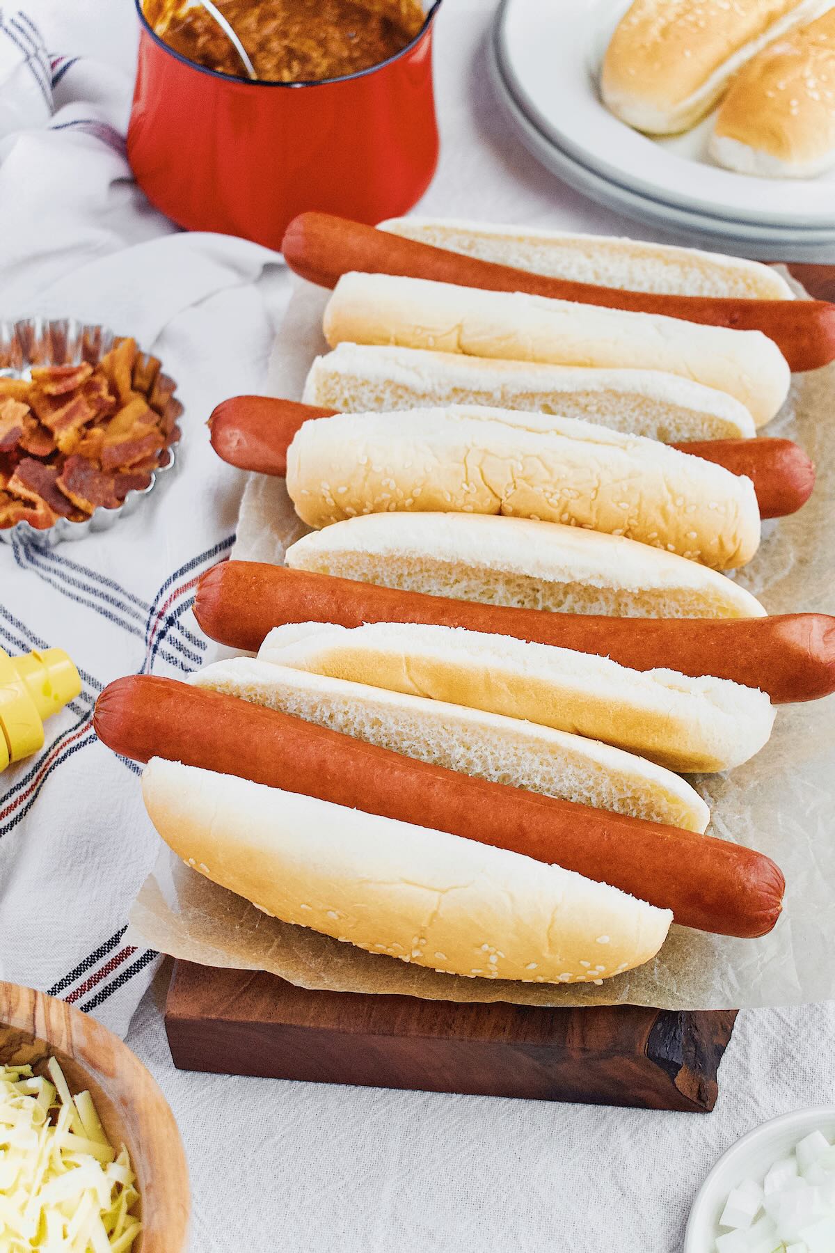 Perfectly steamed hot dogs lined up on a board, ready to be topped to any preferance.