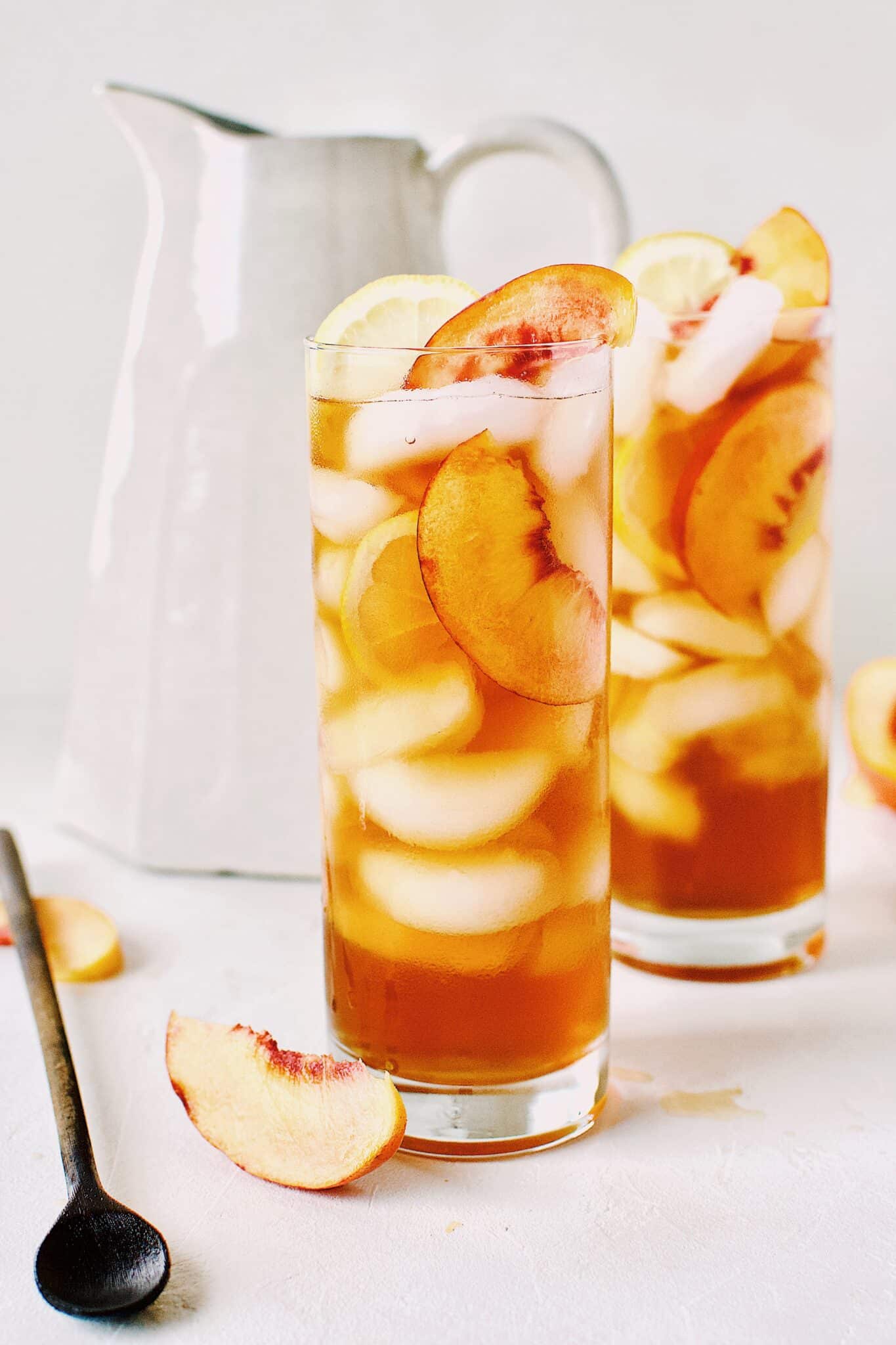 Peach Sweet Tea served up in an ice filled glass with peach and lemon slices inside.