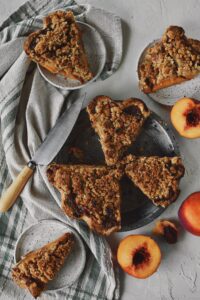 Looking down at the spiced peach pie, that has been sliced, with some slices on plates and some still in the pie tin.