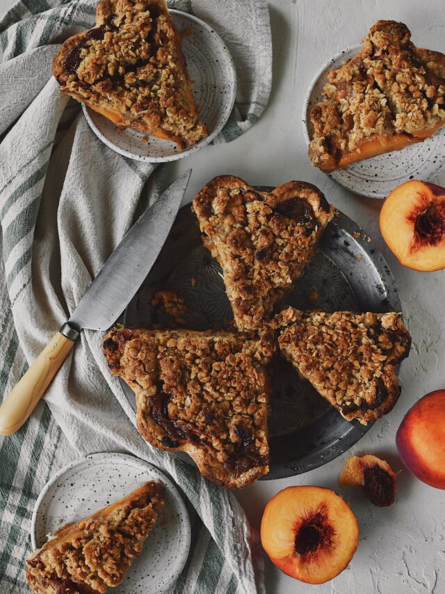 Looking down at the spiced peach pie, that has been sliced, with some slices on plates and some still in the pie tin.