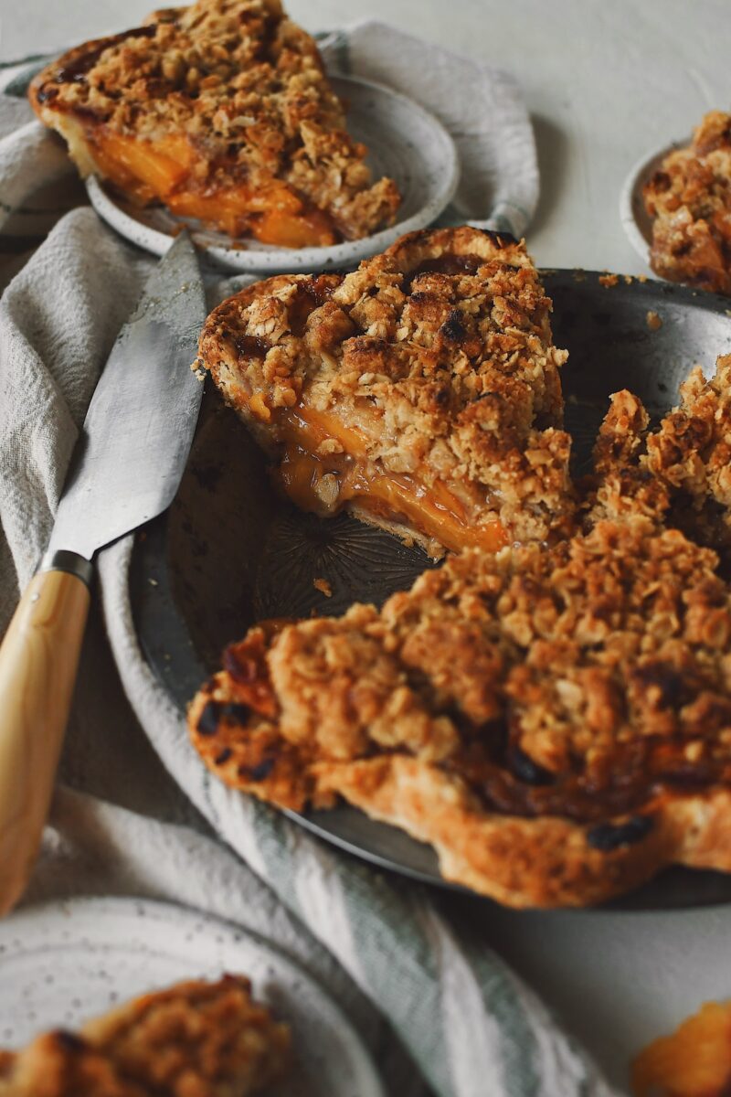 Looking into the spiced peach pie tin, seeing the layers of peaches and crumble topping.