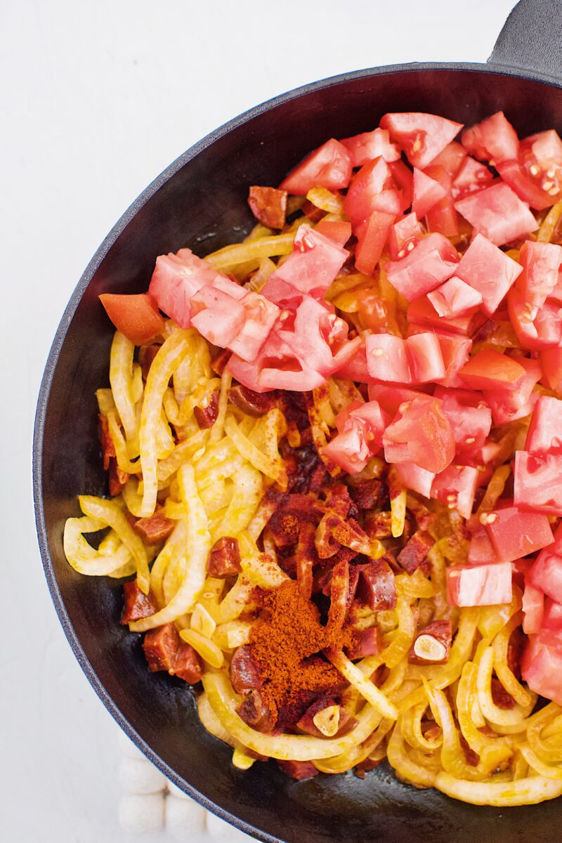 Adding in diced tomato and paprika to the softened onions, garlic and chorizo