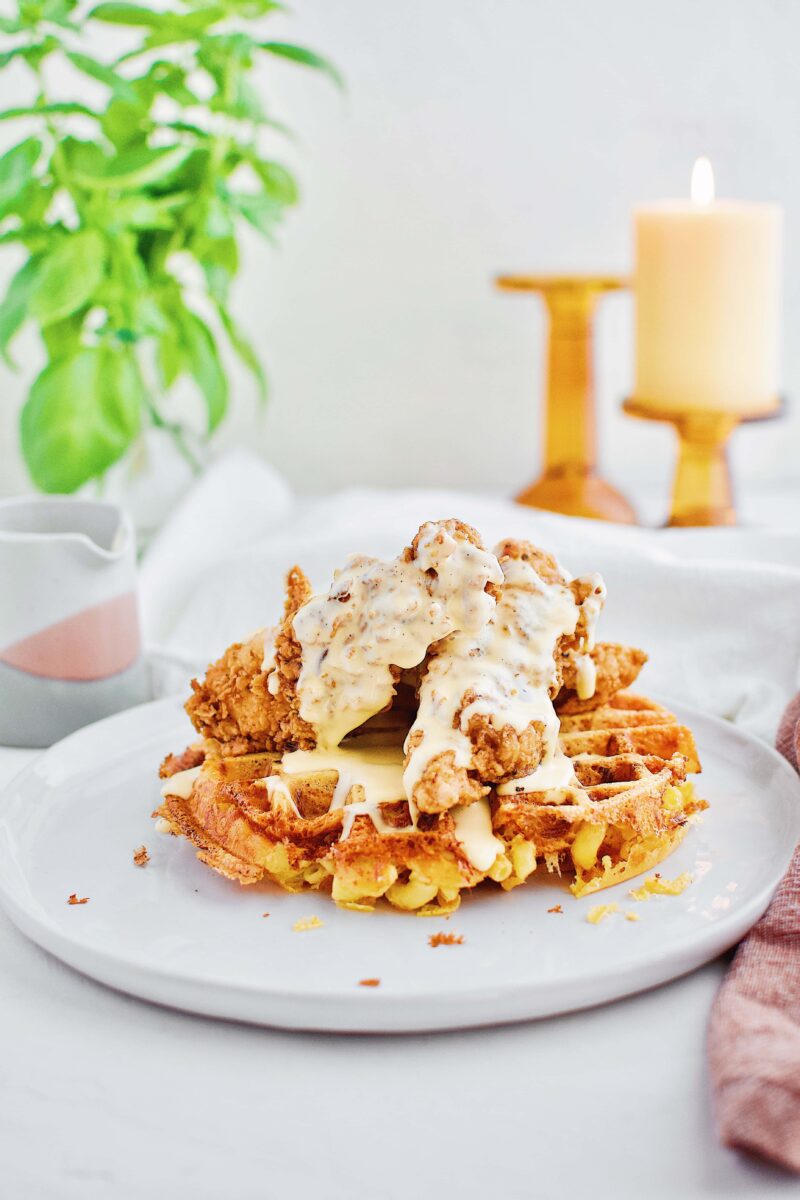 Waffle made of macaroni and cheese and topped with southern fried chicken and golden cheddar cheese syrup sauce