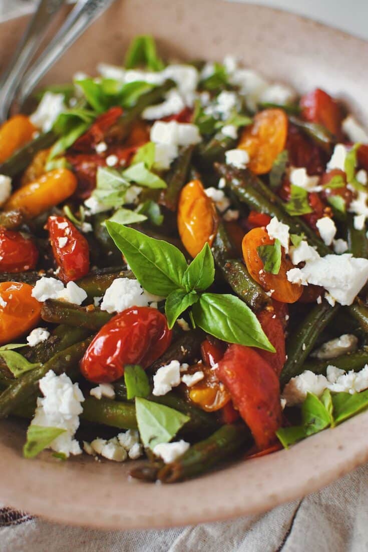 Green Bean Salad, in a serving bowl, topped with feta and basil, ready to eat.