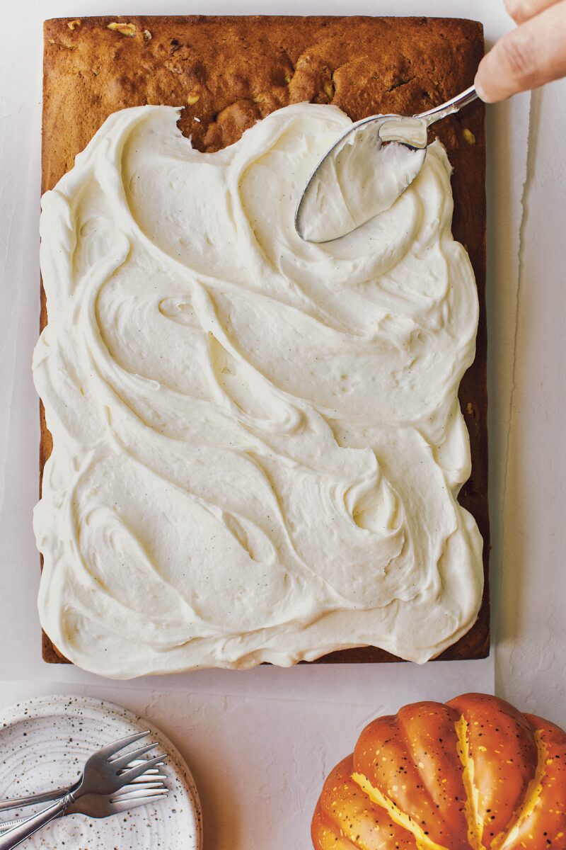 spreading the frosting over the cake with the back of a spoon