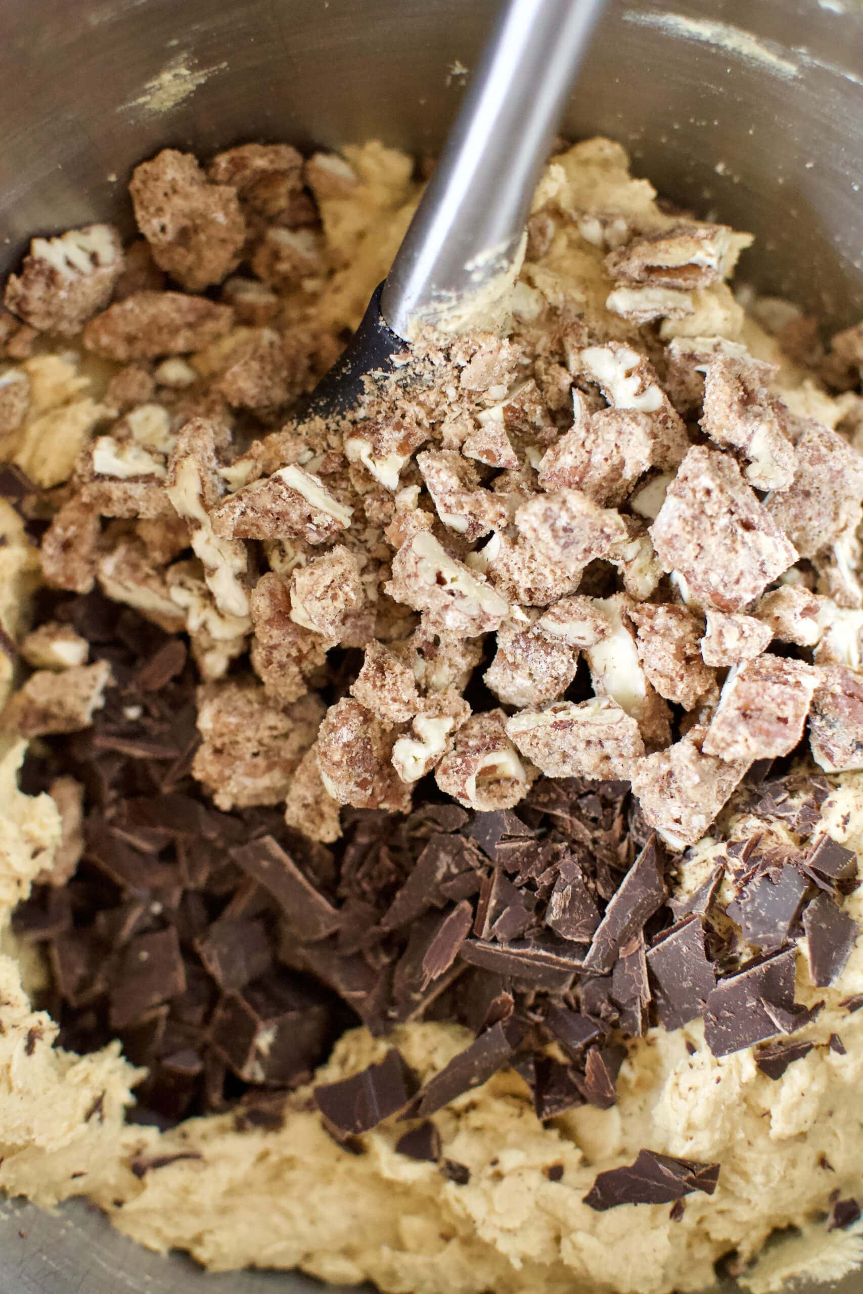 adding the chocolate chunks and candied pecans to the cookie dough