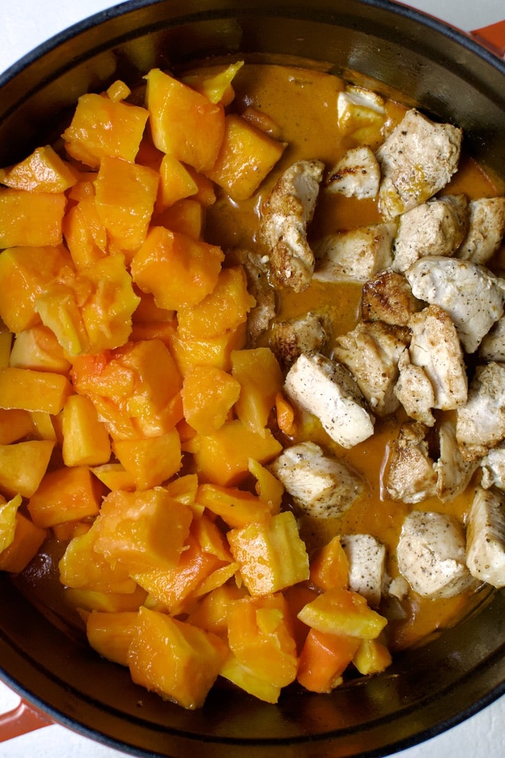 adding the chicken and diced pumpkin to the pot.