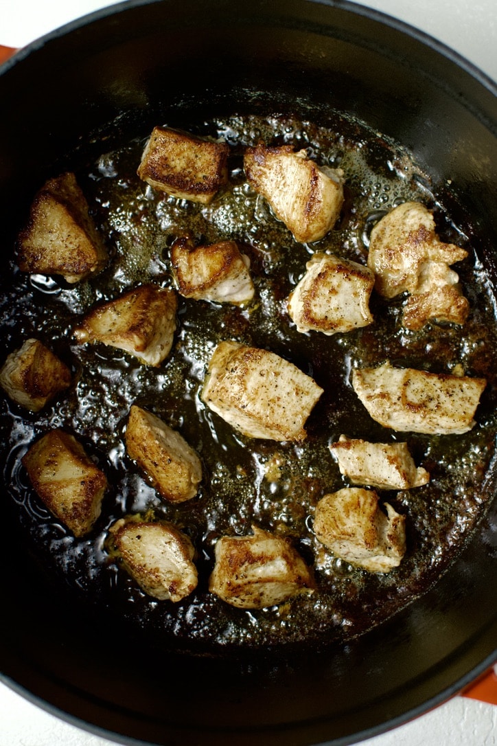 Chicken searing in the bottom of a dutch oven.
