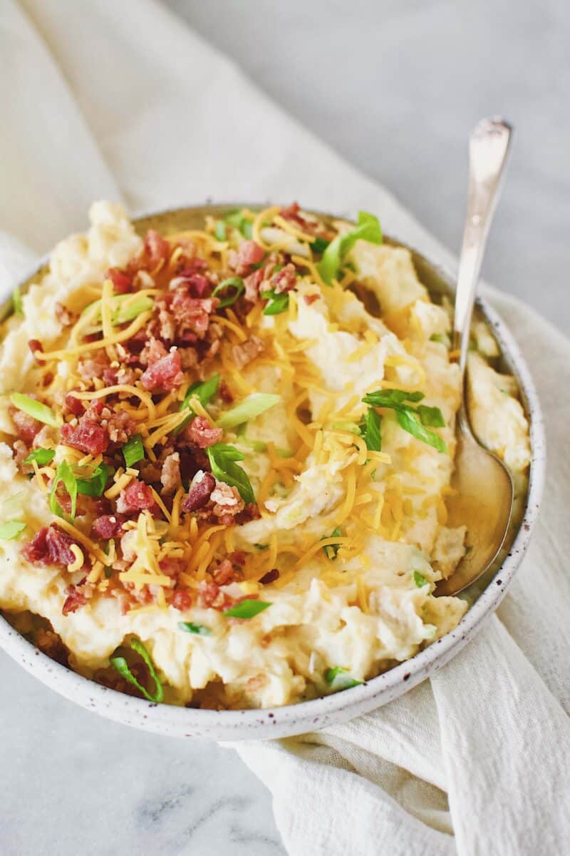 Loaded Baked Potato Mashers topped with bacon, cheese, and green onions in a serving bowl.