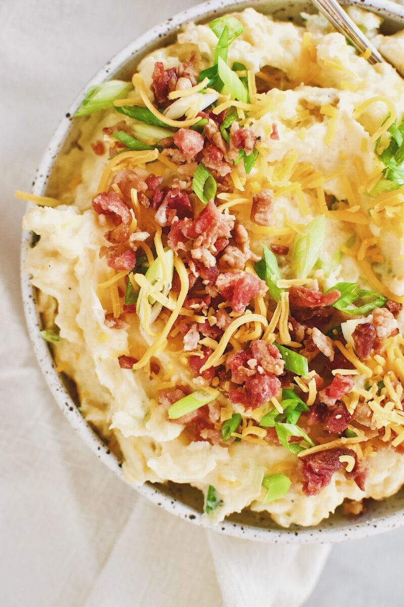 Loaded Baked Potato Mashers topped with bacon, cheese, and green onions in a serving bowl.