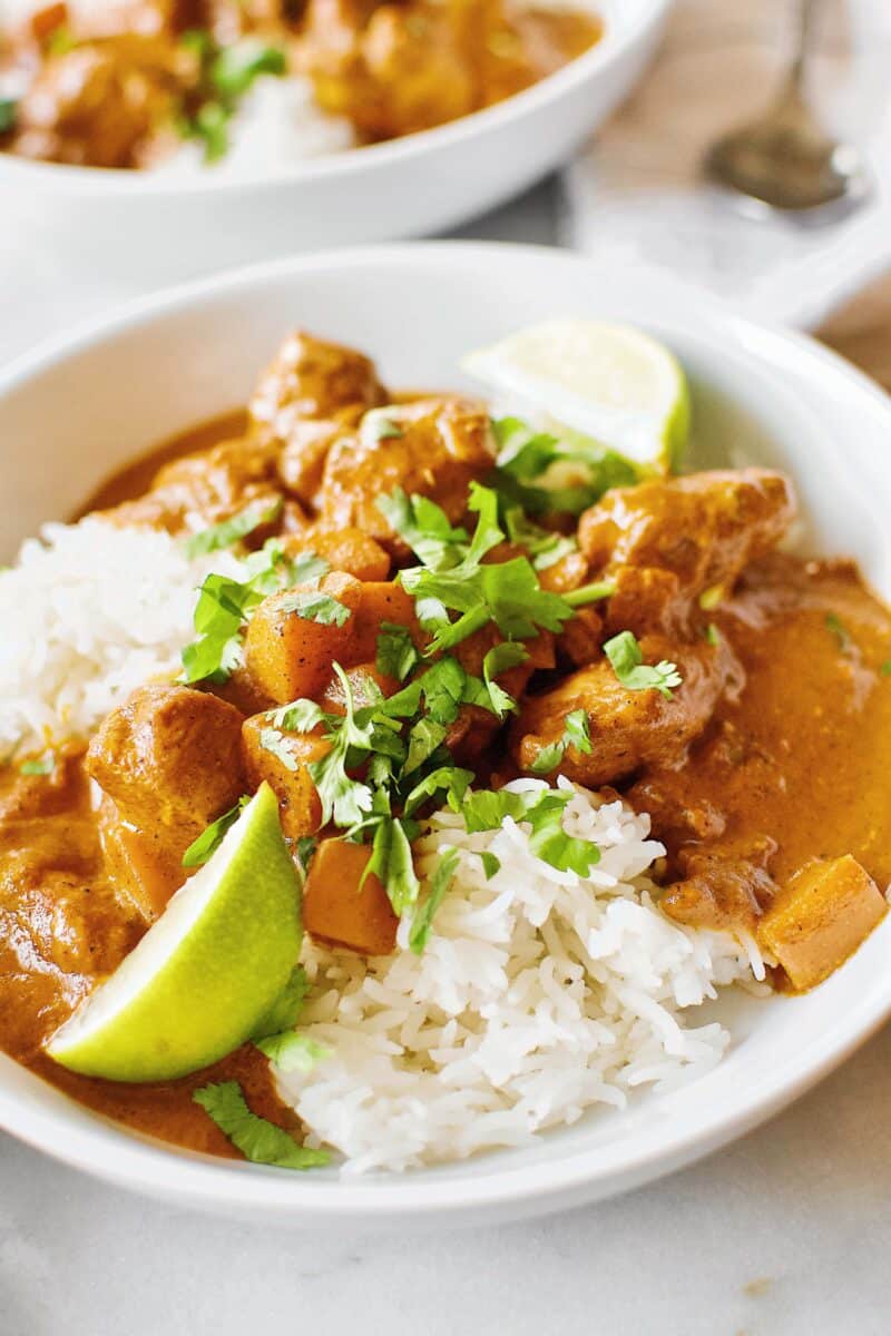 Pumpkin Butter Chicken served of basmati rice with cilantro and lime wedges.