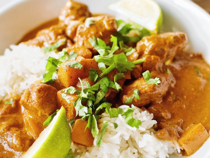 Pumpkin Butter Chicken served of basmati rice with cilantro and lime wedges.