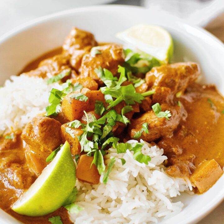 Pumpkin Butter Chicken served of basmati rice with cilantro and lime wedges.
