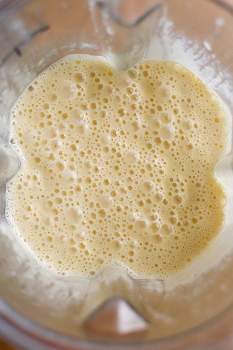 Overhead image of golden cheddar syrup in a blender.