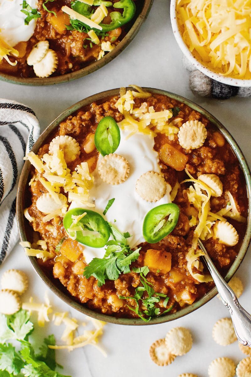 One bowl of Pumpkin Chili garnished with oyster crackers, cilantro, jalapeno and cheese.