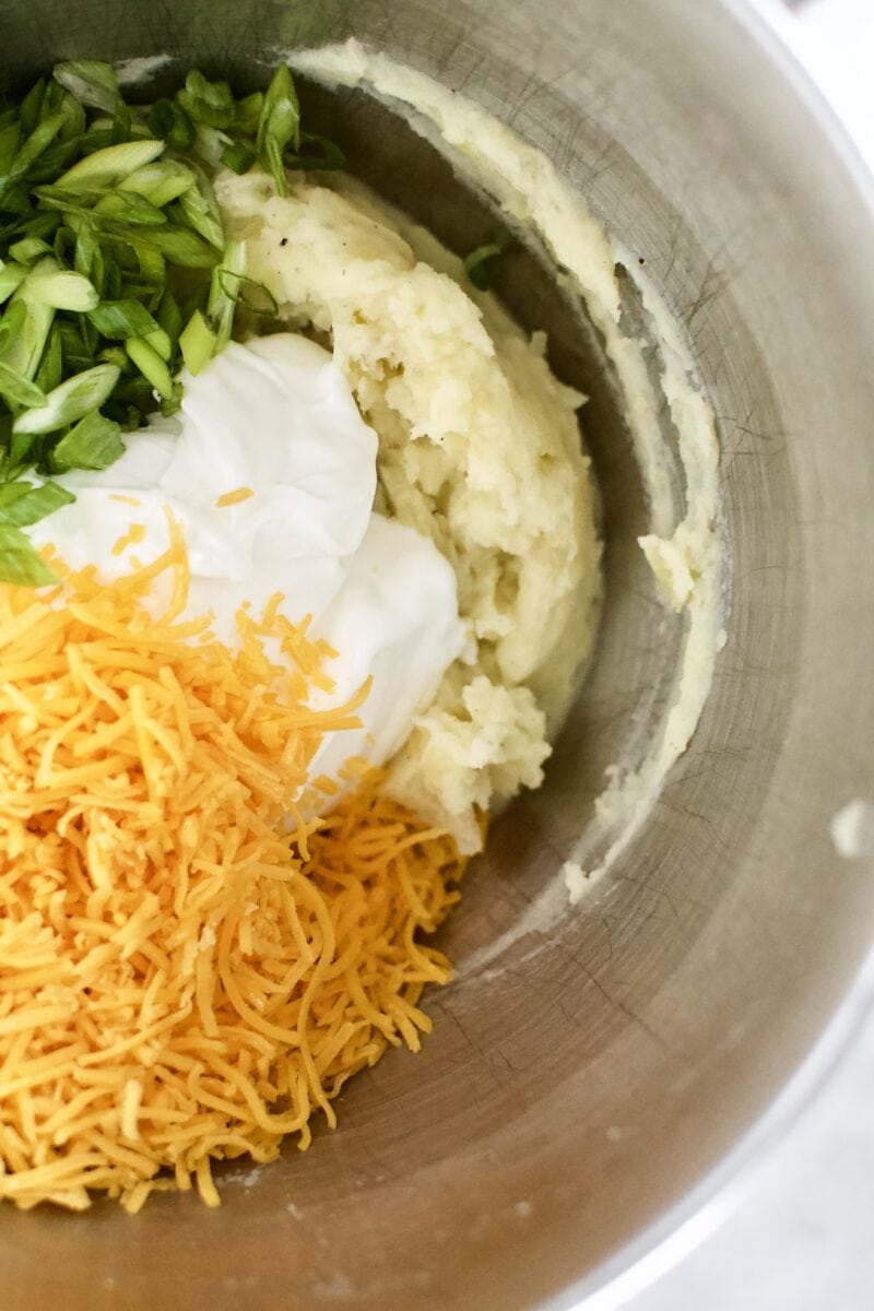 adding the sour cream, cheese, and green onions into the bowl and whipping.