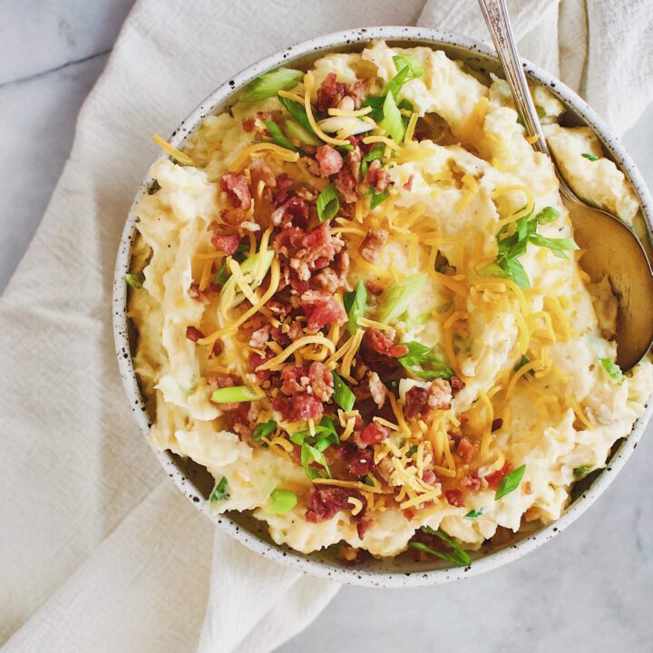 Loaded Baked Potato Mashers topped with bacon, cheese, and green onions in a serving bowl.