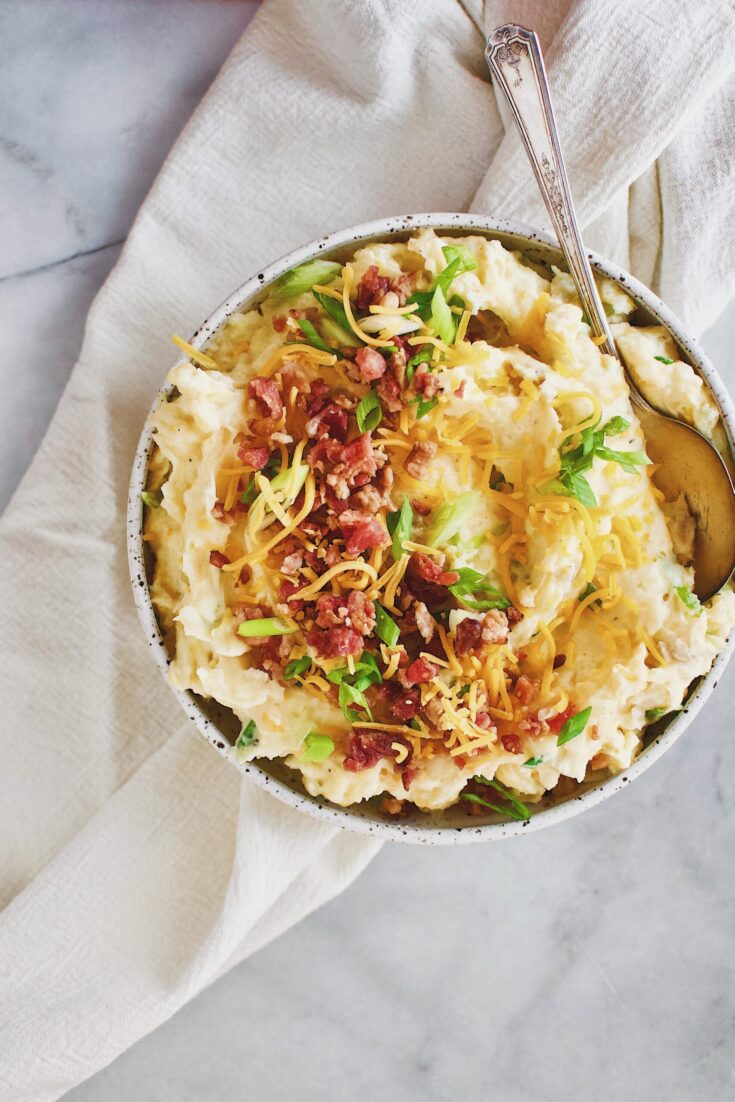 Loaded Baked Potato Mashers topped with bacon, cheese, and green onions in a serving bowl.