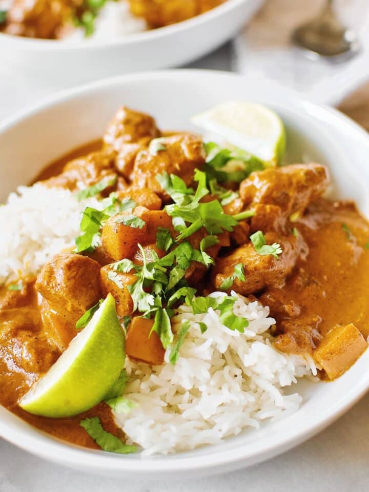 Pumpkin Butter Chicken served with basmati rice, cilantro, and lime wedges.