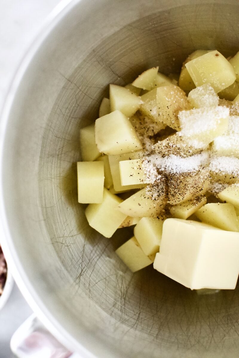 First step in the potato whipping process. Cooked Potatoes, butter, salt, and pepper in the mixing bowl.