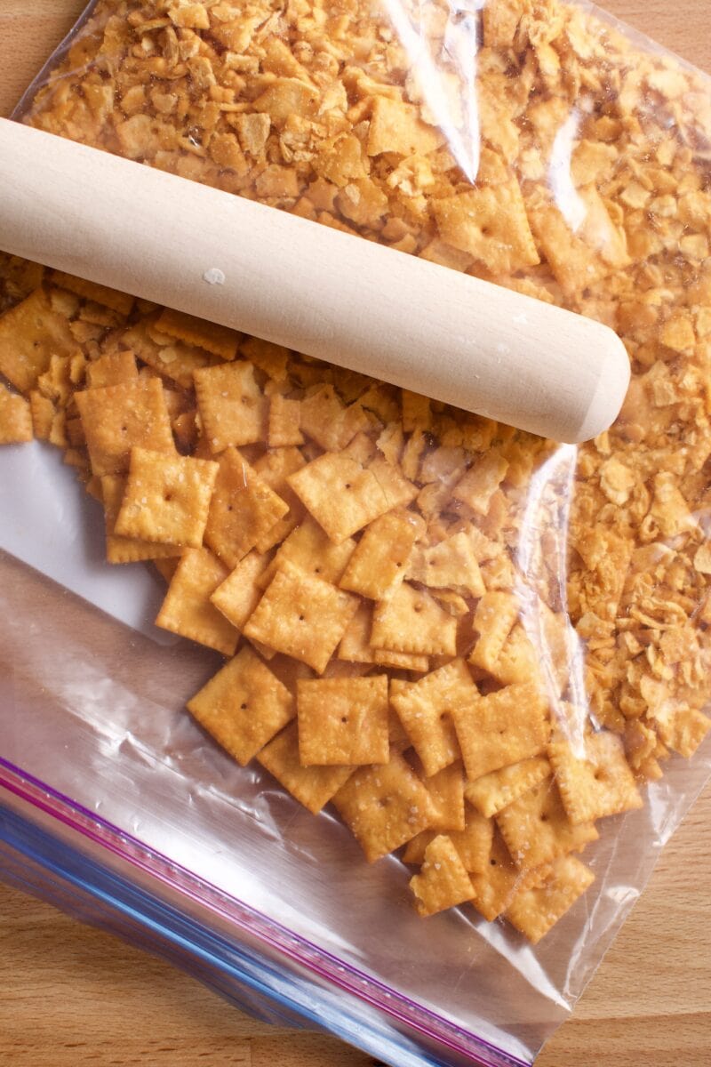 crushing cheez-it crackers in a bag with a rolling pin.