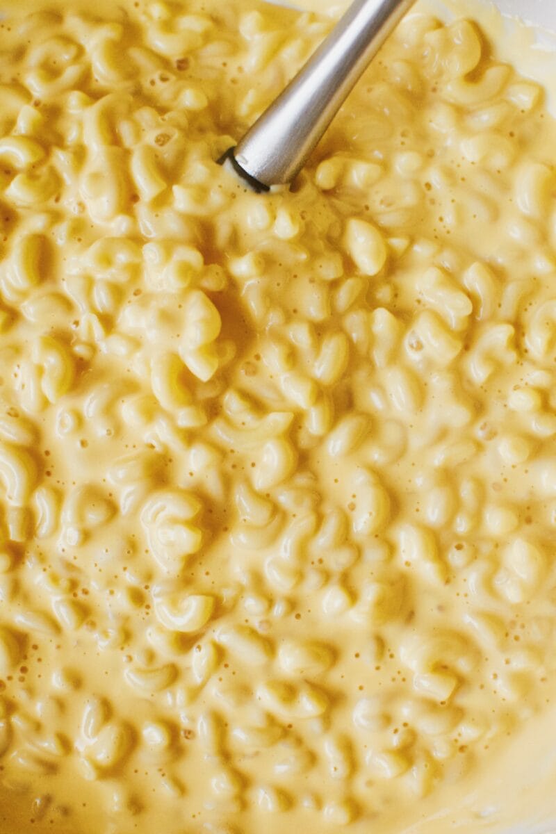 Cooked macaroni and cheddar syrup mixed together in a bowl.