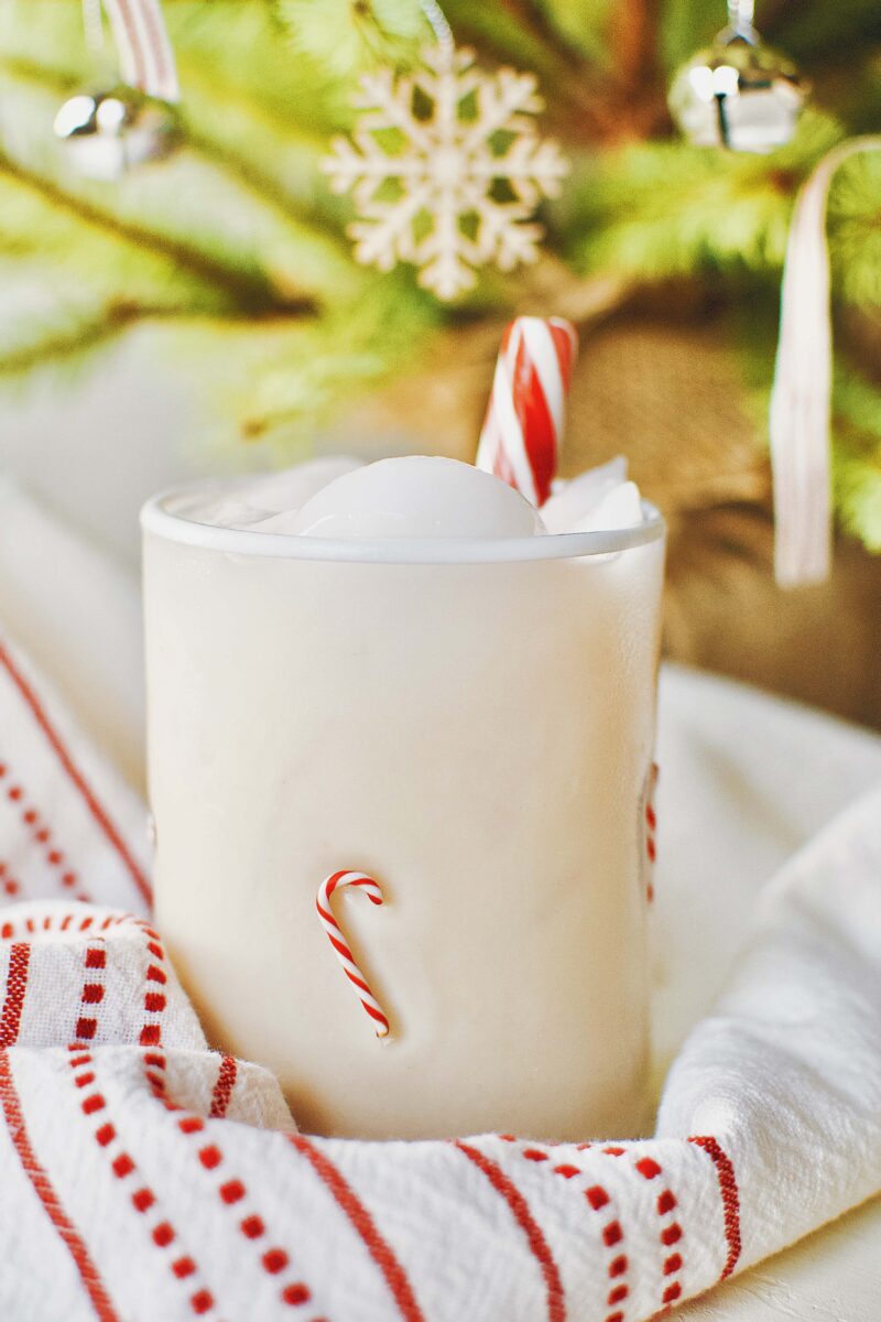 Peppermint Chai Eggnog Cocktail nestled under a Christmas tree.