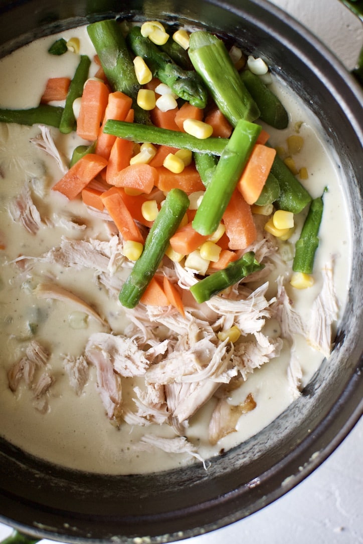 Adding the chicken and frozen veggies to the chicken pot pie filling.