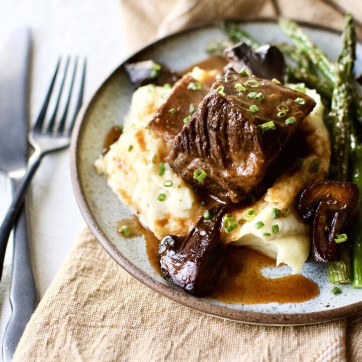 Red Wine Braised Short Ribs on a bed of mashed potatoes with broiled asparagus around them.