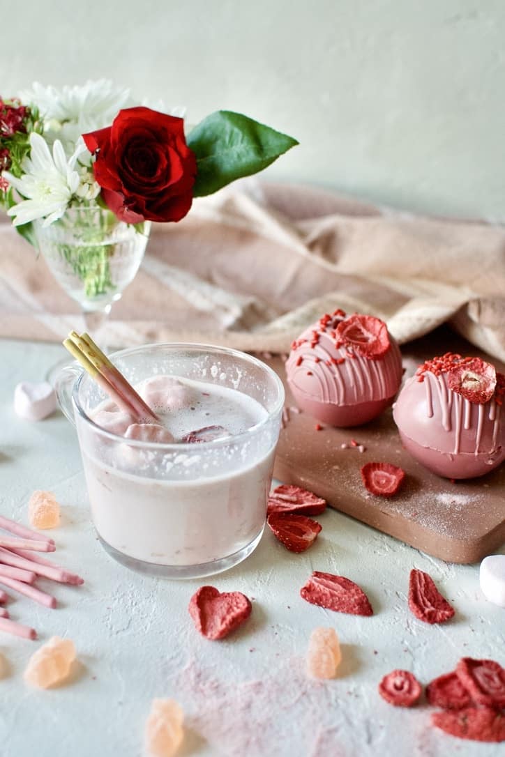 Pink Hot Chocolate in a mug with heart shaped marshmallows after using a Pink Hot Chocolate Bomb to to make the hot cocoa.