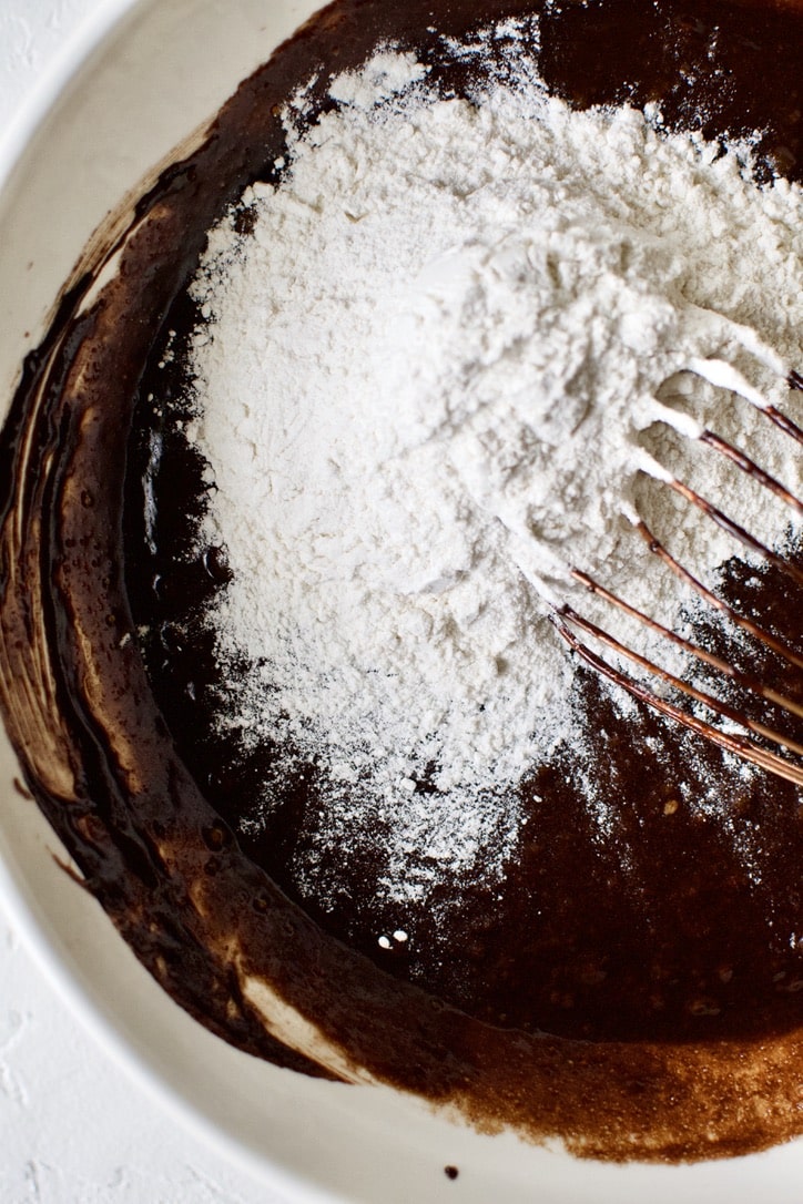 adding the flour to the classic brownie batter wet ingredients.