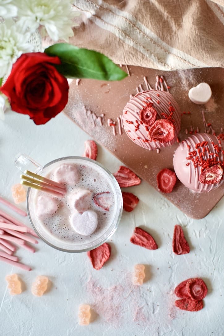 Pink Hot Chocolate in a mug with heart shaped marshmallows after using a Pink Hot Chocolate Bomb to to make the hot cocoa.