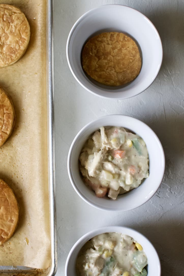 Layering puff pastry rounds and chicken pot pie filling in the serving dish.