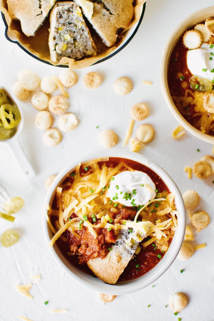 Spicy Texas Chili in two bowls surrounded by various toppings.