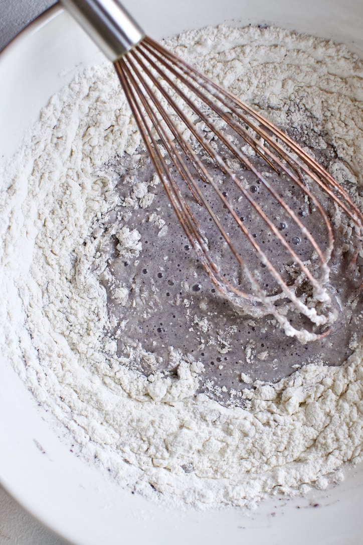 Dry ingredients for cornbread being whisked into the wet ingredients.