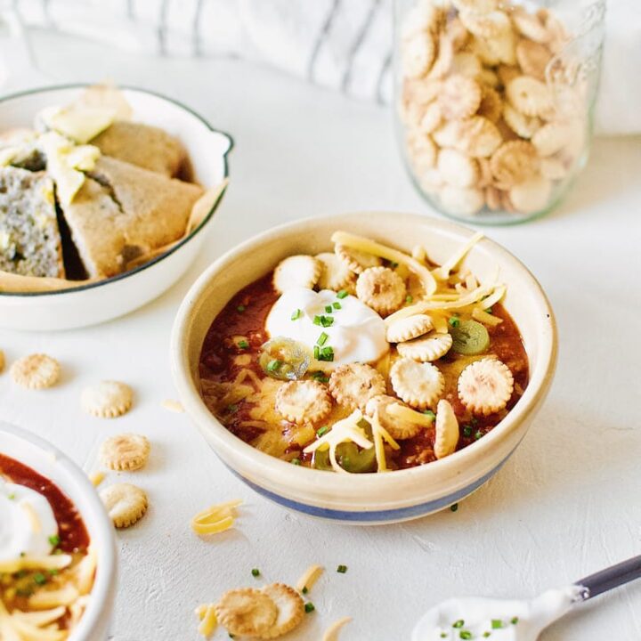 Spicy Texas Chili in two bowls surrounded by various toppings.