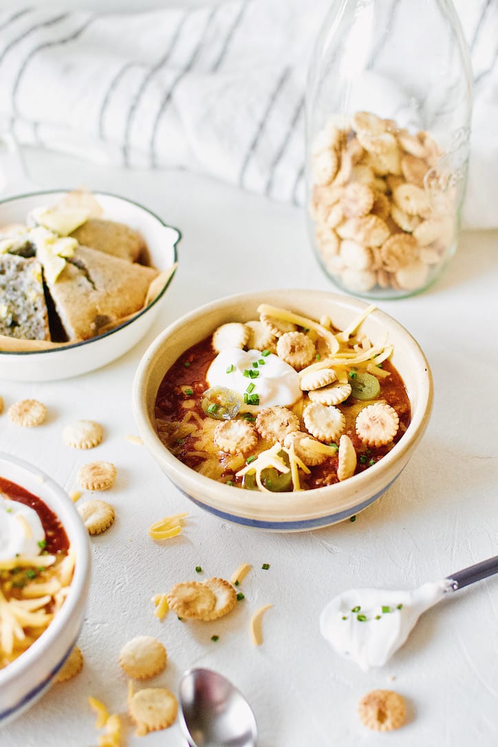 Spicy Texas Chili in two bowls surrounded by various toppings.