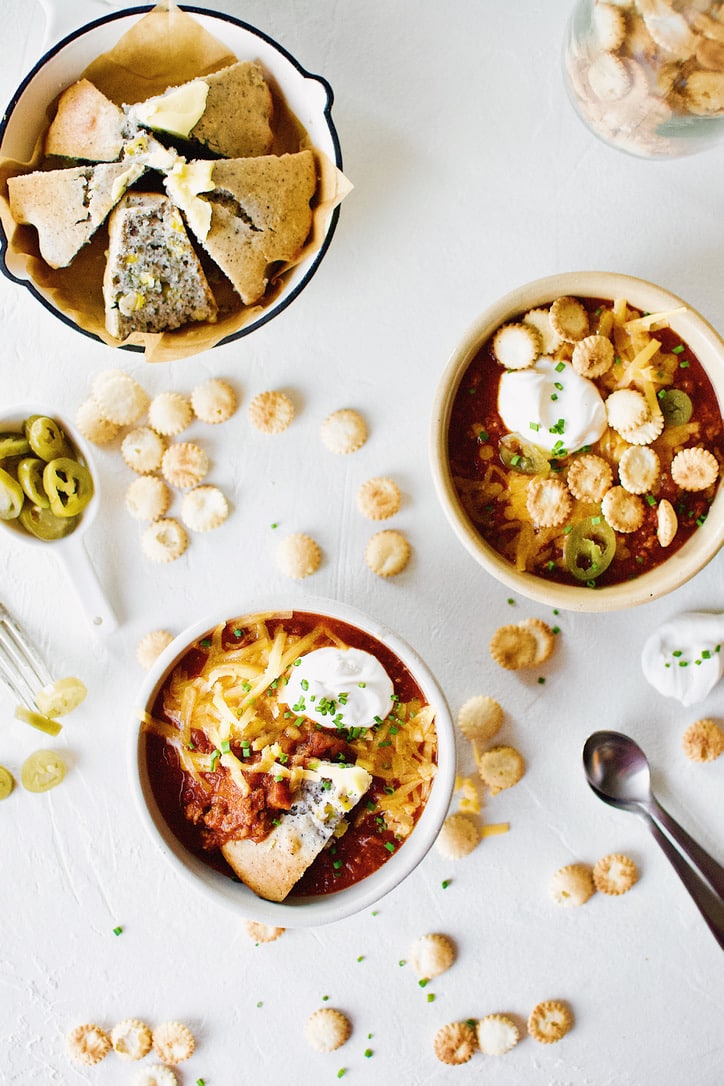 Spicy Texas Chili in two bowls surrounded by various toppings.